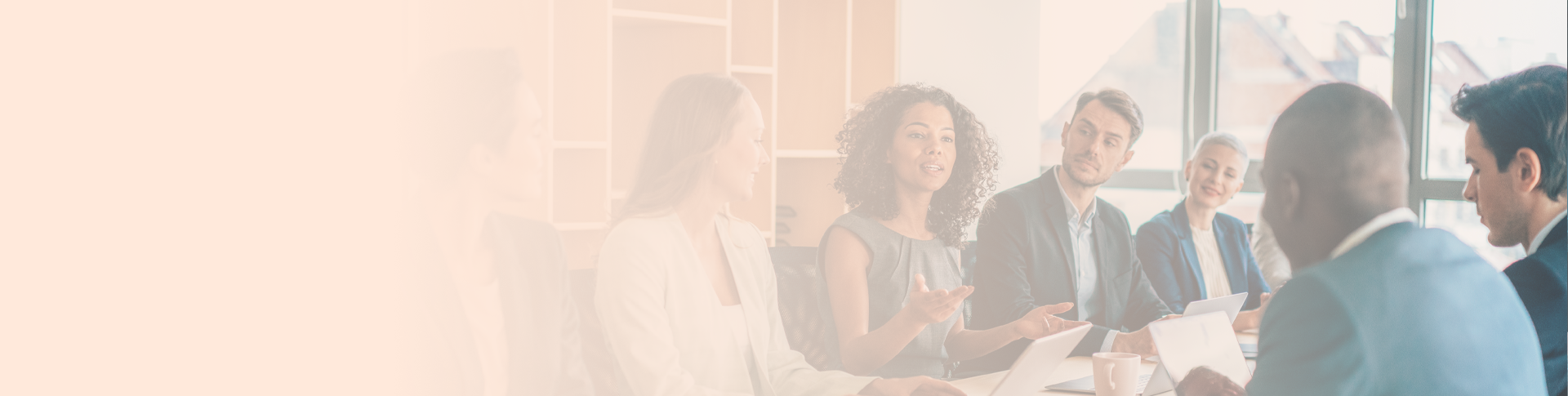 people in office attire sitting at a table in a meeting