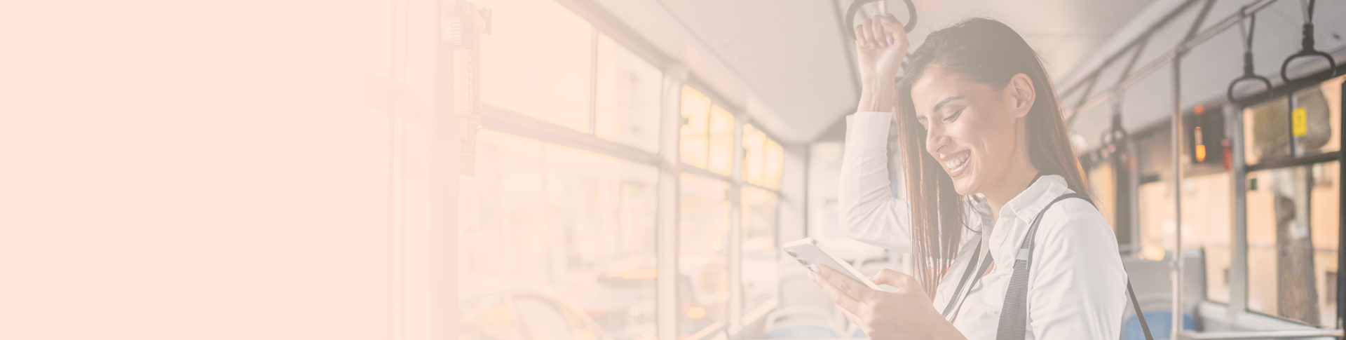 A happy woman on a public transport. She is standing and reading on a tablet.