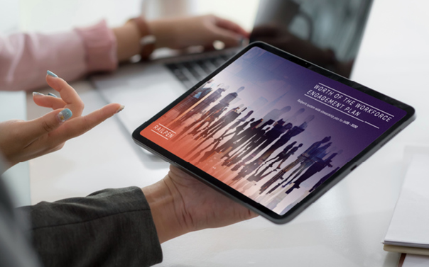 Tablet showing the ‘Worth of the Workforce Engagement Plan’ cover, held during a workplace discussion.