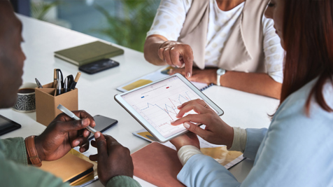 Tablet showing graphs is viewed by three office workers