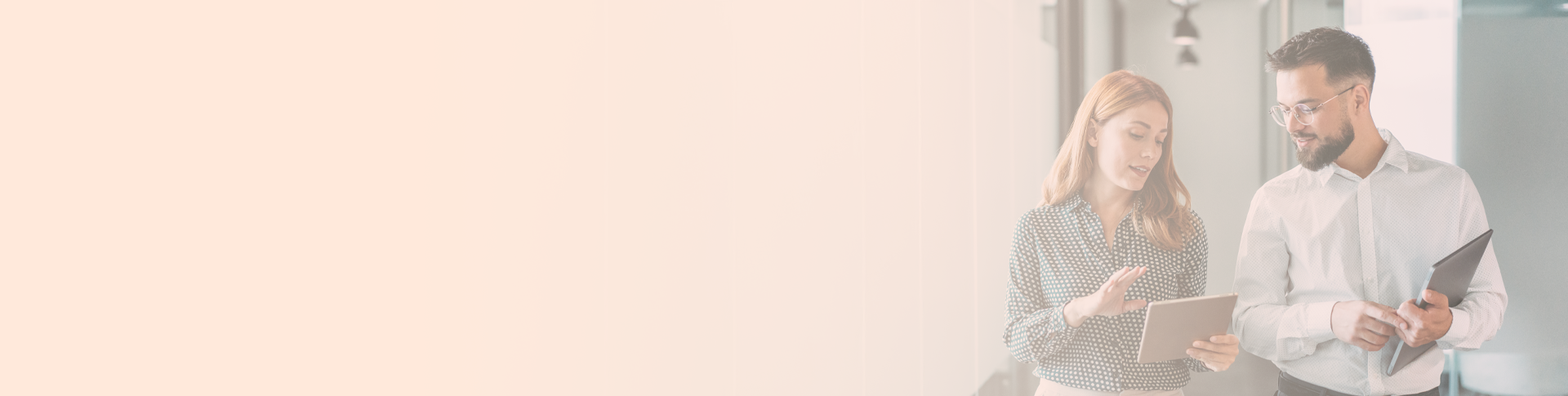 a man and a woman in an office. A woman is holding a tablet and explaining something