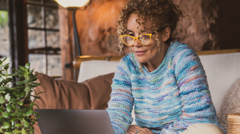 Woman in blue knit jumper using a laptop at home